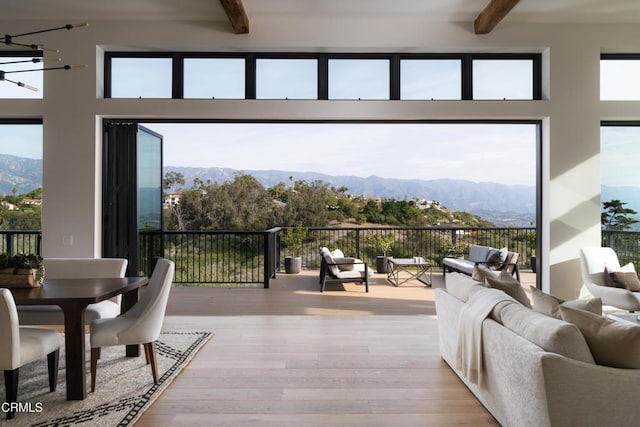 interior space featuring a wealth of natural light, beam ceiling, a mountain view, and light wood-type flooring