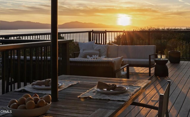 deck at dusk featuring a water view