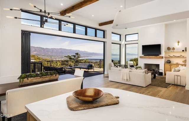 interior space with an inviting chandelier, a high ceiling, a mountain view, beamed ceiling, and light wood-type flooring