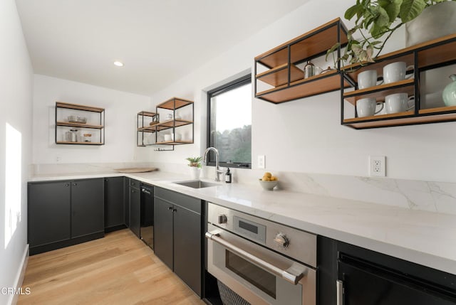 kitchen featuring light stone counters, sink, light hardwood / wood-style floors, and oven