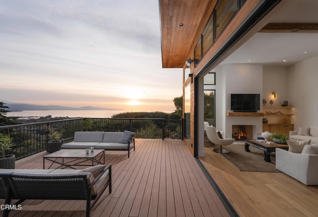 deck with a water view and an outdoor living space with a fireplace