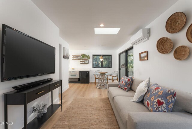 living room featuring a wall mounted air conditioner, a skylight, and light hardwood / wood-style flooring