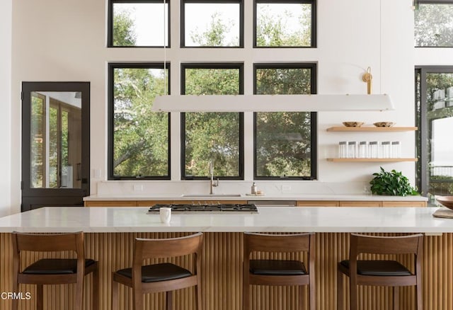 bar featuring a healthy amount of sunlight, sink, and stainless steel gas stovetop