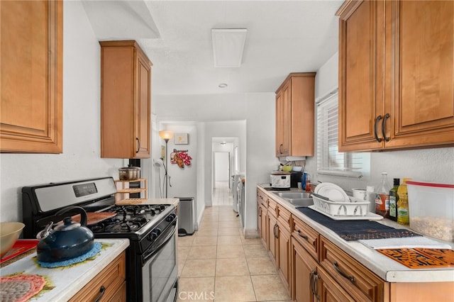 kitchen featuring light tile patterned flooring, stainless steel range with gas cooktop, and sink