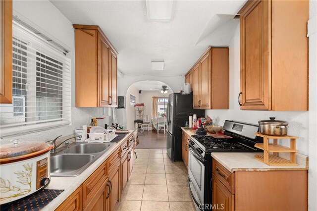 kitchen featuring stainless steel appliances, sink, light tile patterned floors, and ceiling fan