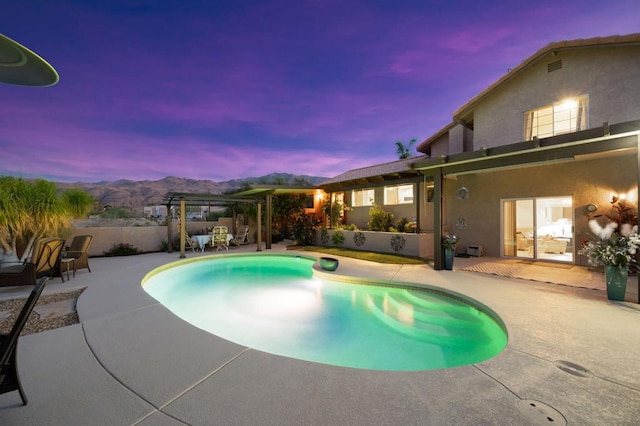 pool at dusk featuring a patio area and a mountain view