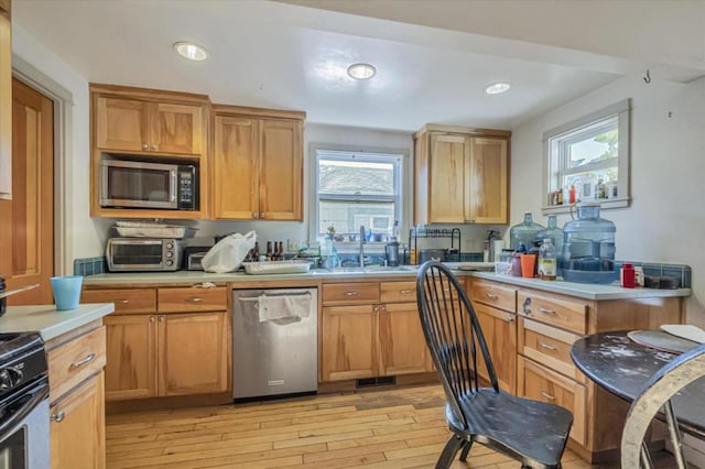 kitchen featuring appliances with stainless steel finishes, sink, and light wood-type flooring