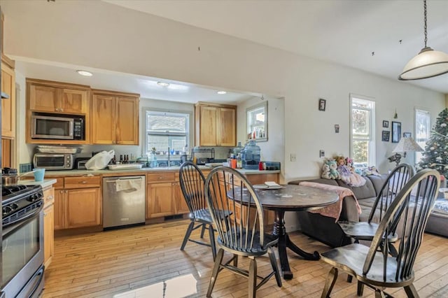 kitchen featuring pendant lighting, stainless steel appliances, and light hardwood / wood-style floors