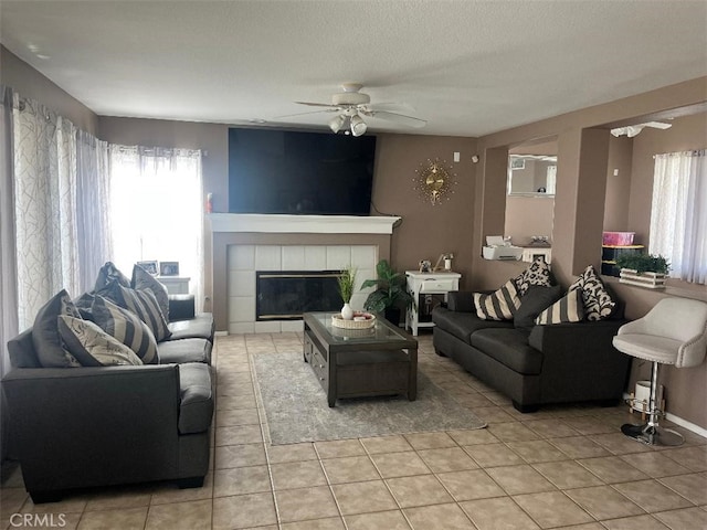 tiled living room with a tiled fireplace, a textured ceiling, and ceiling fan