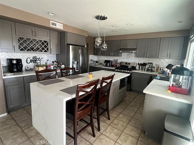 kitchen featuring pendant lighting, appliances with stainless steel finishes, a kitchen island, and gray cabinetry