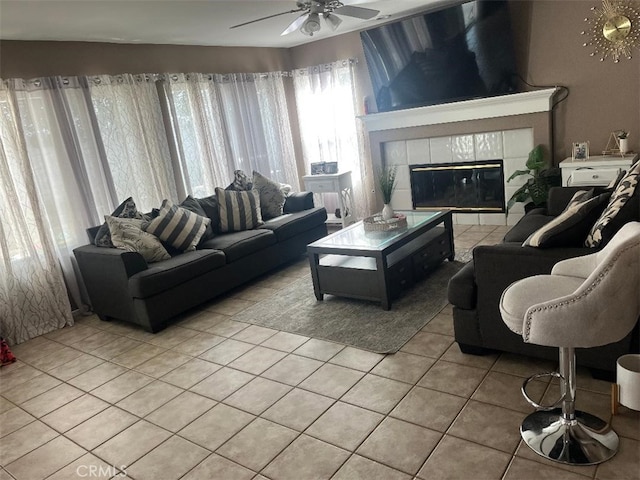 living room with a tiled fireplace, light tile patterned floors, and ceiling fan