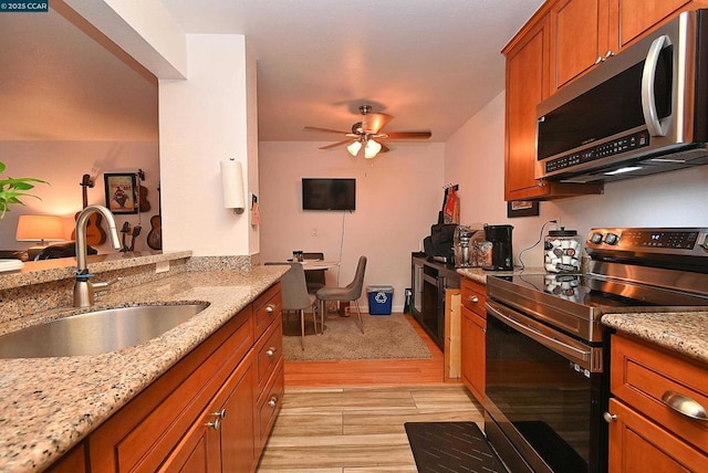 kitchen featuring ceiling fan, appliances with stainless steel finishes, light stone countertops, and sink