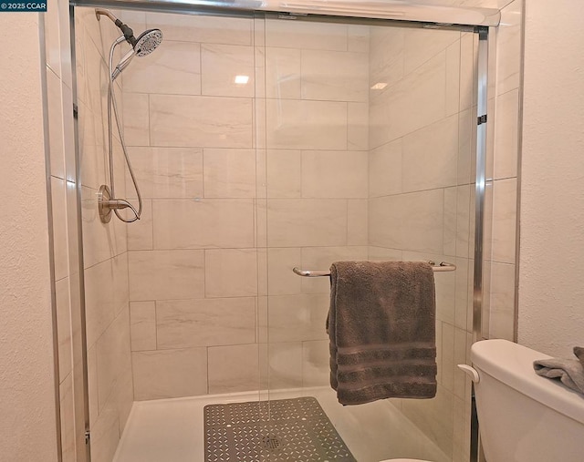 bathroom featuring a shower with shower door and toilet