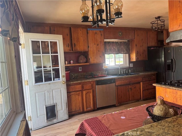 kitchen featuring dishwasher, sink, a chandelier, light wood-type flooring, and black refrigerator with ice dispenser