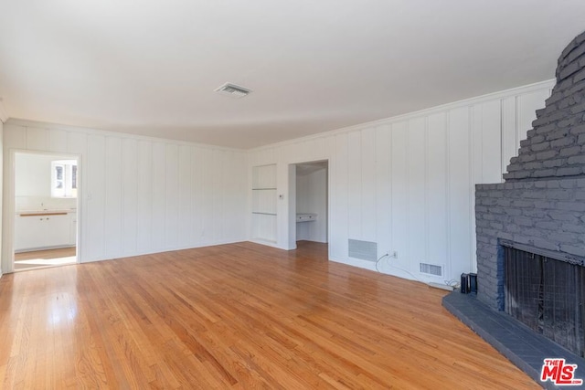 unfurnished living room featuring light hardwood / wood-style floors, ornamental molding, and a fireplace