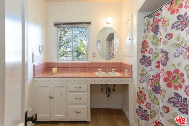 bathroom featuring walk in shower, hardwood / wood-style flooring, tasteful backsplash, and sink