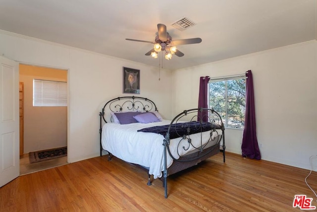 bedroom with ceiling fan, crown molding, and hardwood / wood-style flooring