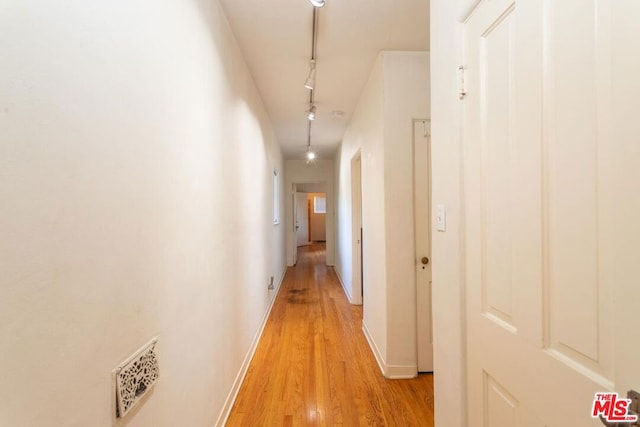 corridor with track lighting and light hardwood / wood-style floors