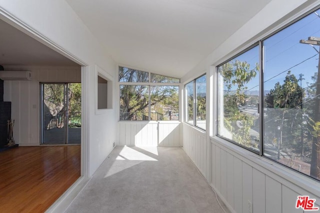 unfurnished sunroom featuring lofted ceiling and a wall mounted air conditioner