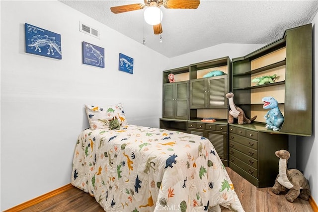 bedroom with dark hardwood / wood-style flooring, ceiling fan, vaulted ceiling, and a textured ceiling