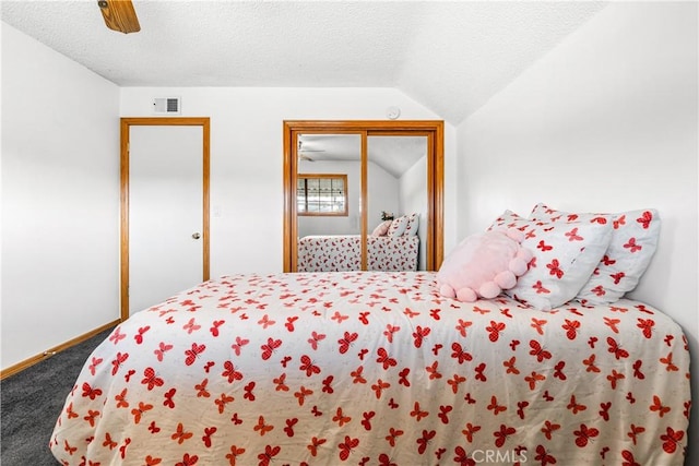 carpeted bedroom with ceiling fan, vaulted ceiling, a closet, and a textured ceiling