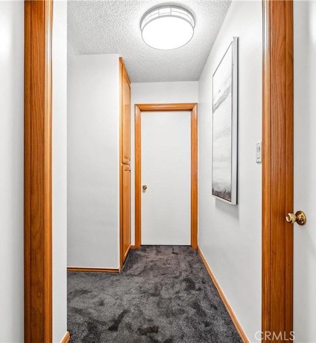 hallway featuring carpet and a textured ceiling