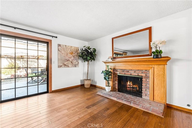 living area with a fireplace, wood-type flooring, and a textured ceiling