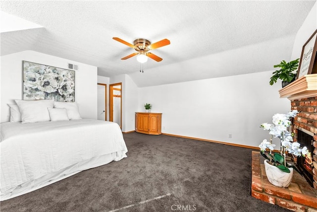 carpeted bedroom with ceiling fan, lofted ceiling, a textured ceiling, and a fireplace