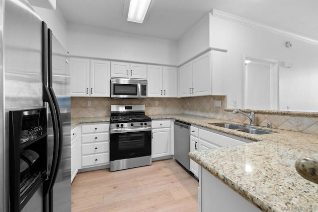 kitchen with light stone countertops, appliances with stainless steel finishes, white cabinetry, decorative backsplash, and sink