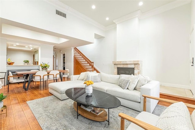 living room with a fireplace, crown molding, and light hardwood / wood-style flooring