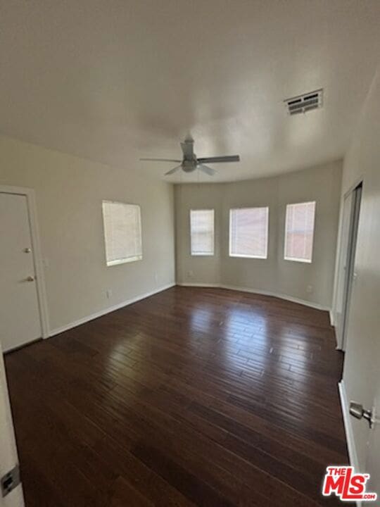 empty room with ceiling fan and dark wood-type flooring