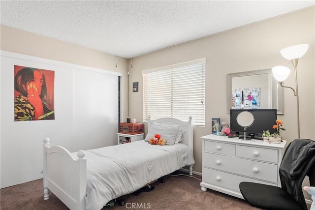 bedroom featuring dark colored carpet and a textured ceiling