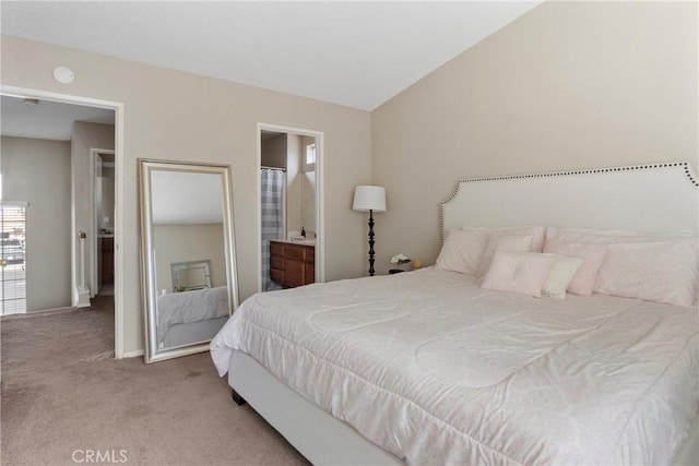 carpeted bedroom with ensuite bath and vaulted ceiling