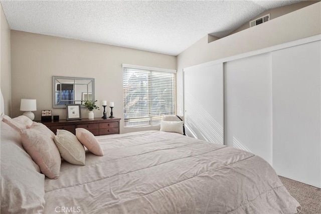 bedroom with a textured ceiling, carpet floors, a closet, and lofted ceiling