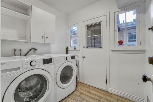 clothes washing area featuring washer and dryer and cabinets