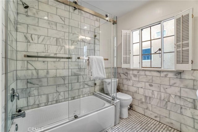 bathroom featuring toilet, enclosed tub / shower combo, tile walls, and tile patterned flooring