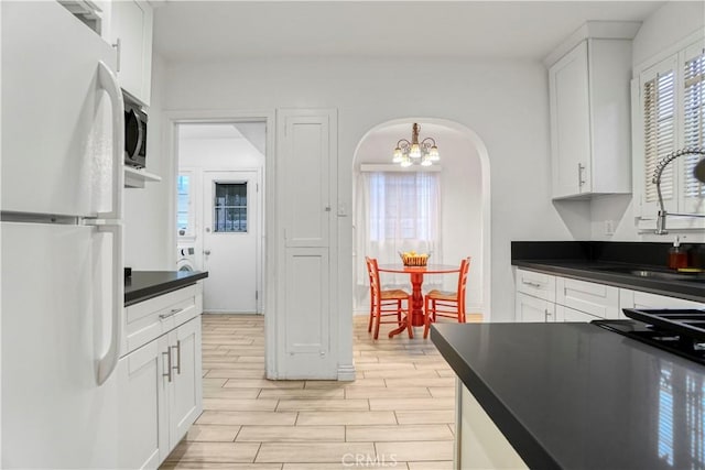 kitchen with sink, white cabinetry, stainless steel microwave, and white refrigerator