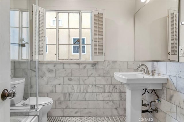 bathroom with sink, tile walls, and toilet