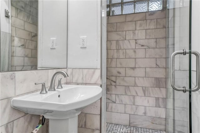 bathroom featuring decorative backsplash, tile walls, an enclosed shower, and sink