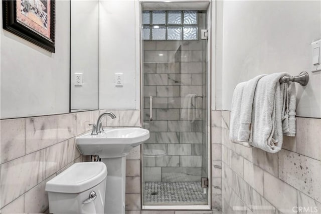 bathroom with toilet, tile walls, walk in shower, and sink