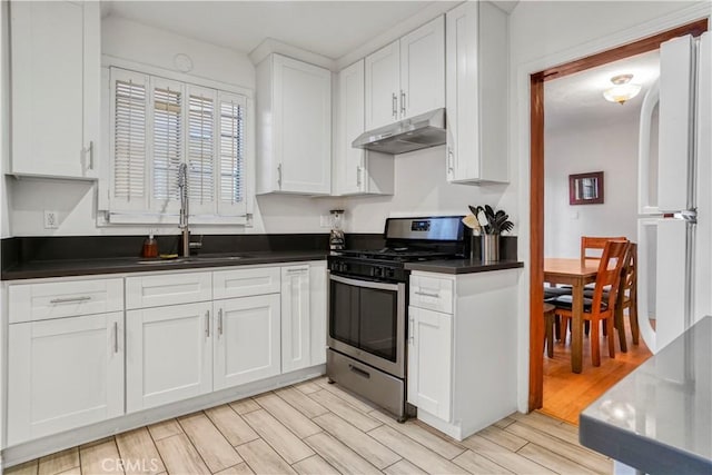 kitchen with sink, gas range, white refrigerator, and white cabinetry