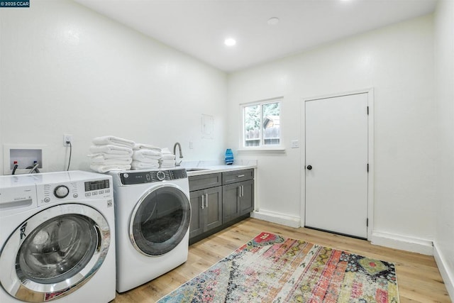 washroom with cabinets, sink, washing machine and dryer, and light wood-type flooring