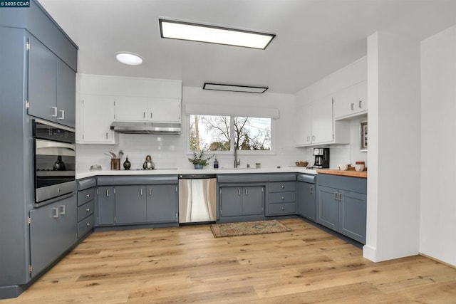 kitchen with gray cabinets, white cabinetry, appliances with stainless steel finishes, and light hardwood / wood-style floors