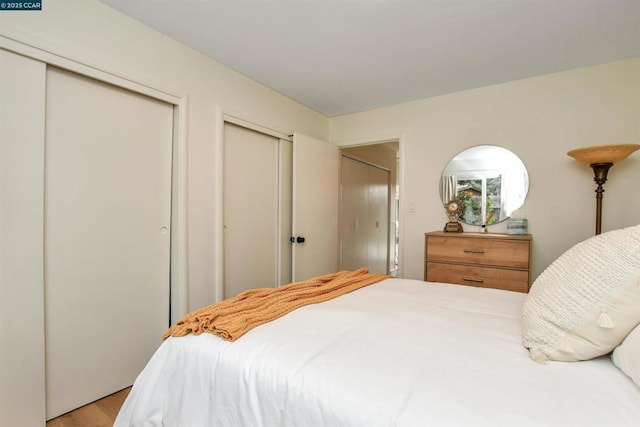 bedroom featuring two closets and light wood-type flooring