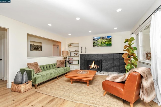 living room featuring a brick fireplace, wood-type flooring, and built in features