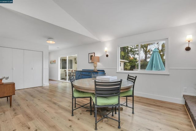 dining space featuring vaulted ceiling and light hardwood / wood-style floors