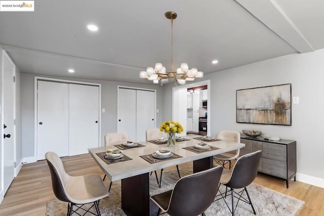 dining room with light wood-type flooring and a notable chandelier