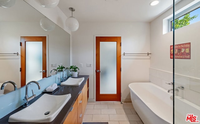 bathroom featuring vanity, tile patterned floors, and a bath