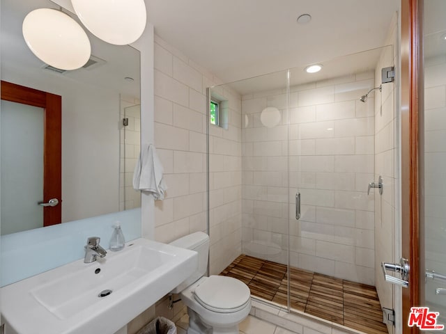 bathroom featuring toilet, an enclosed shower, sink, and tile patterned floors