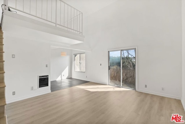 unfurnished living room featuring heating unit, a towering ceiling, and hardwood / wood-style flooring